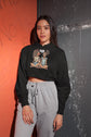 Person wearing a black hoodie with graphic design and gray pants against a colorful background