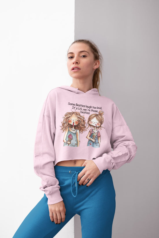 Woman wearing a pink hoodie with cartoon characters and text, standing against a gray background