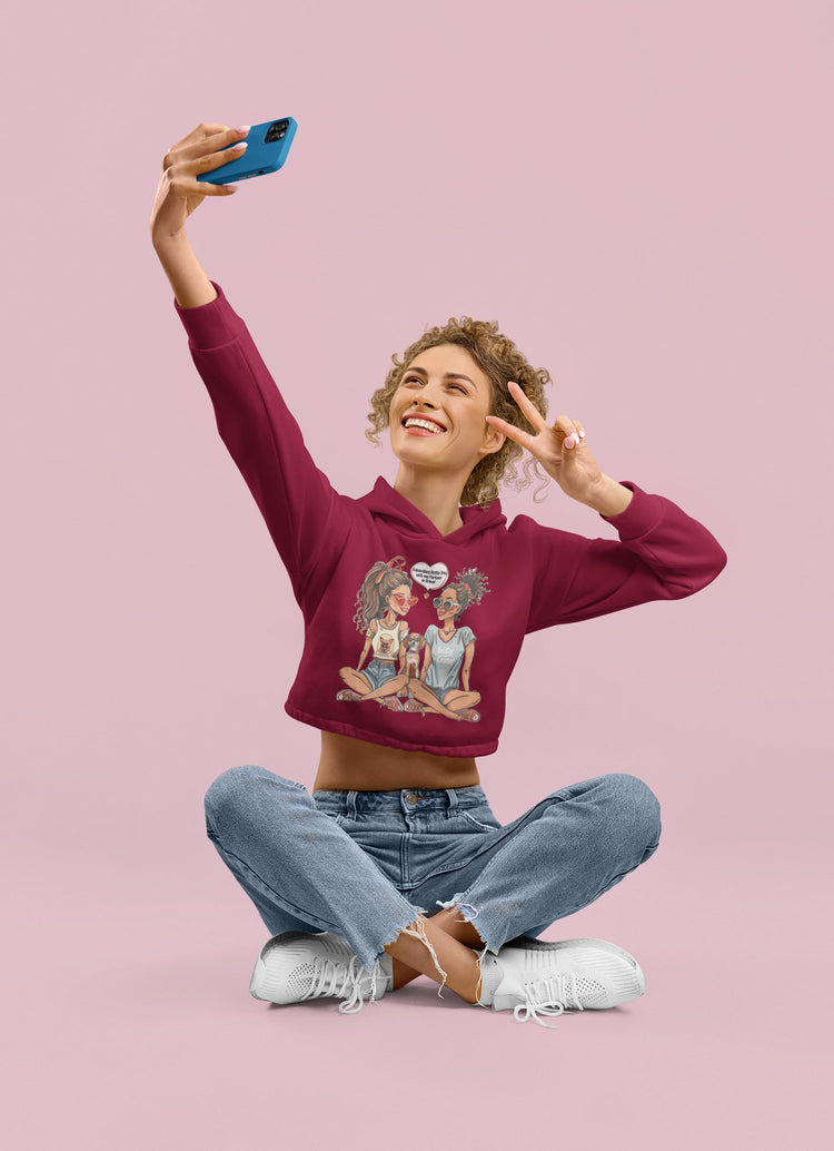 Woman taking a selfie wearing a maroon hoodie with a graphic design on a pink background