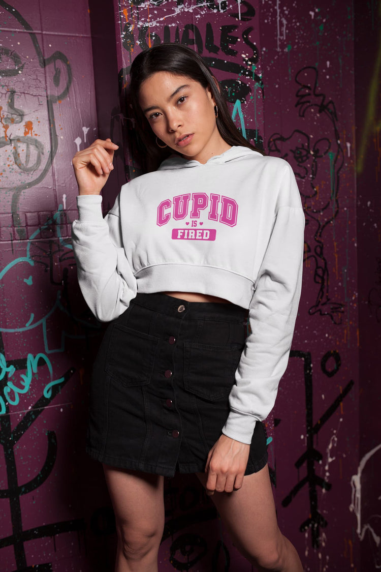 Woman wearing a white hoodie with pink text against a graffiti-covered wall