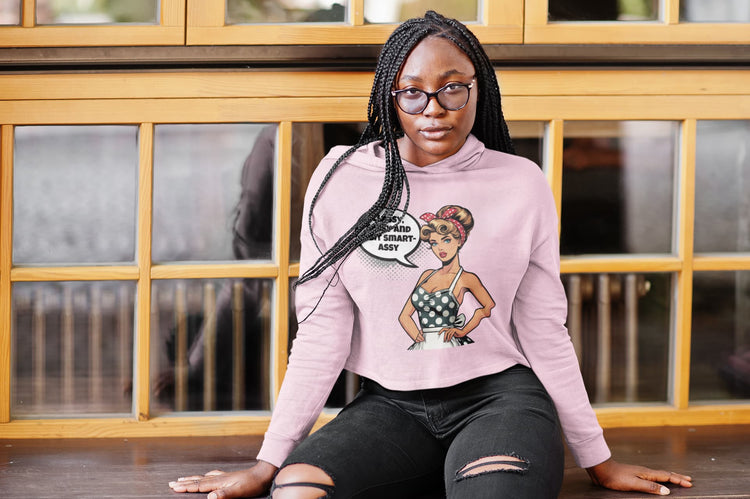Person wearing a pink sweatshirt with a graphic design sitting in front of a wooden window.