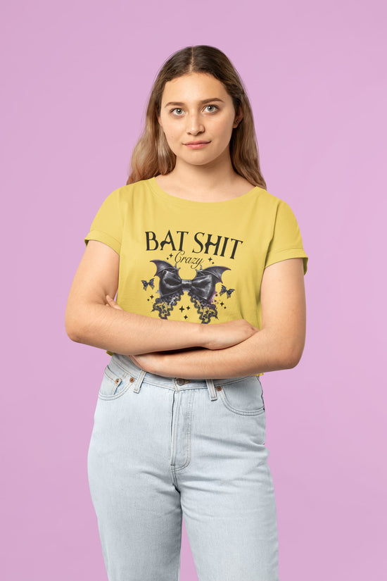 Person wearing a mustard yellow t-shirt with graphic design and text on a pink background