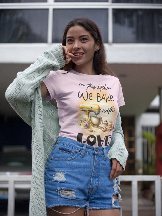 Woman wearing a pink t-shirt with a graphic design and text, standing outdoors.