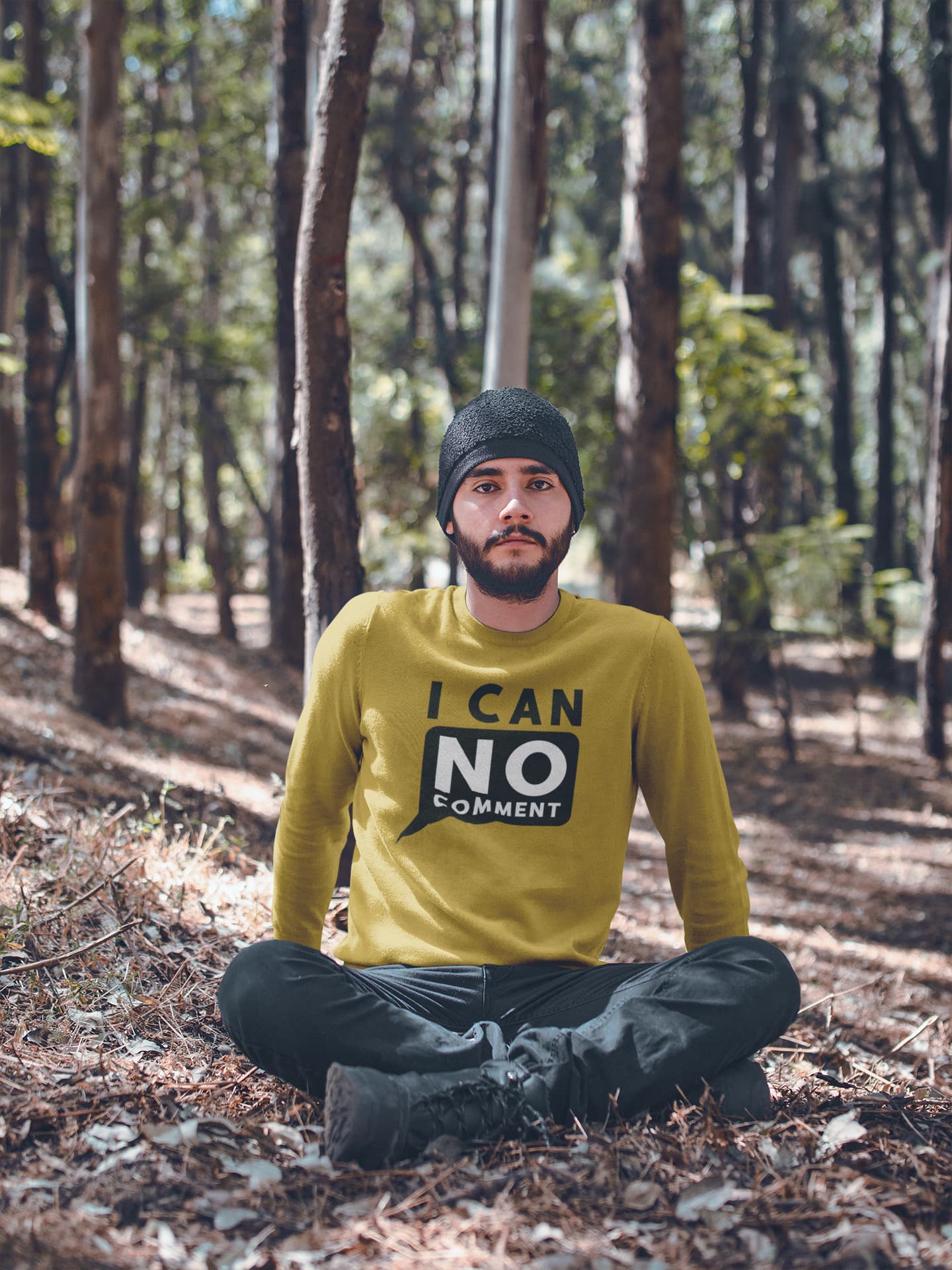 Man sitting in a forest wearing a yellow sweater with text
