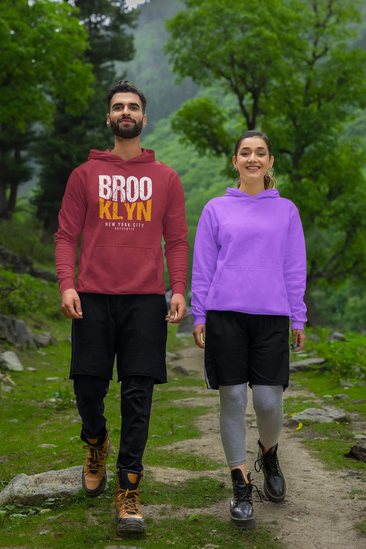 Two people wearing hoodies standing on a trail with a forest background