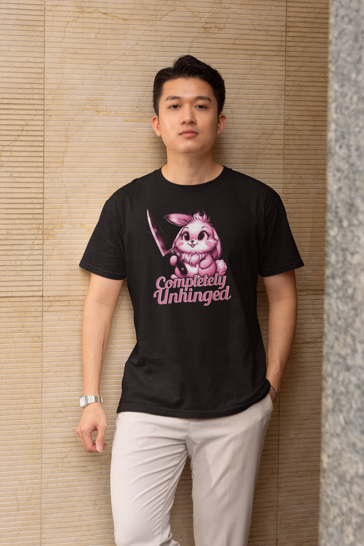 Person wearing a black t-shirt with a graphic design and text, standing against a textured wall.