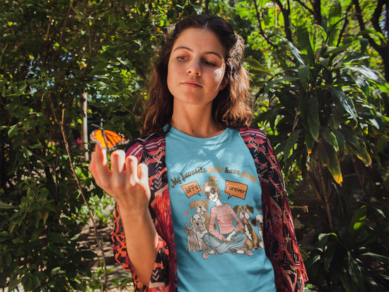Woman holding a butterfly with a graphic t-shirt in a forest setting