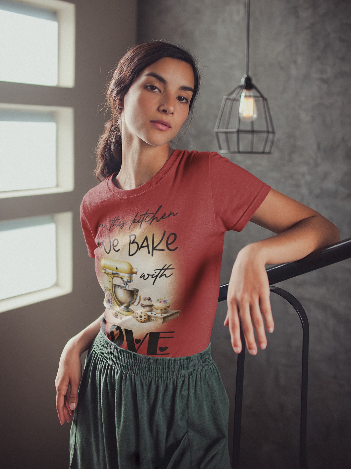 Woman wearing a red t-shirt with a graphic design, standing indoors.