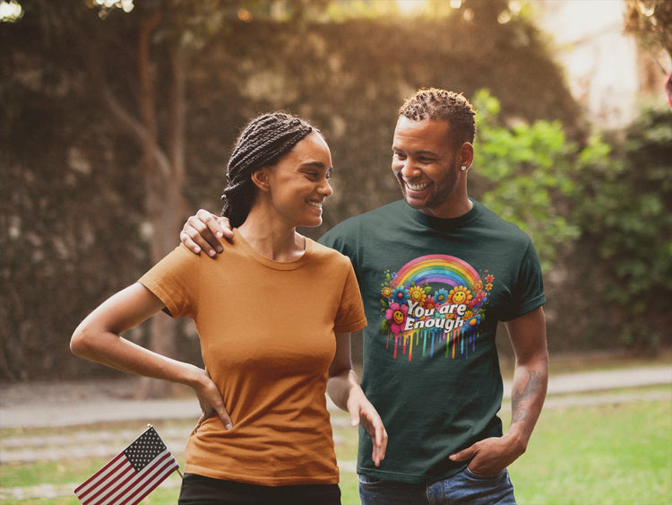 Two people standing outdoors with one wearing a t-shirt with a rainbow design and text.