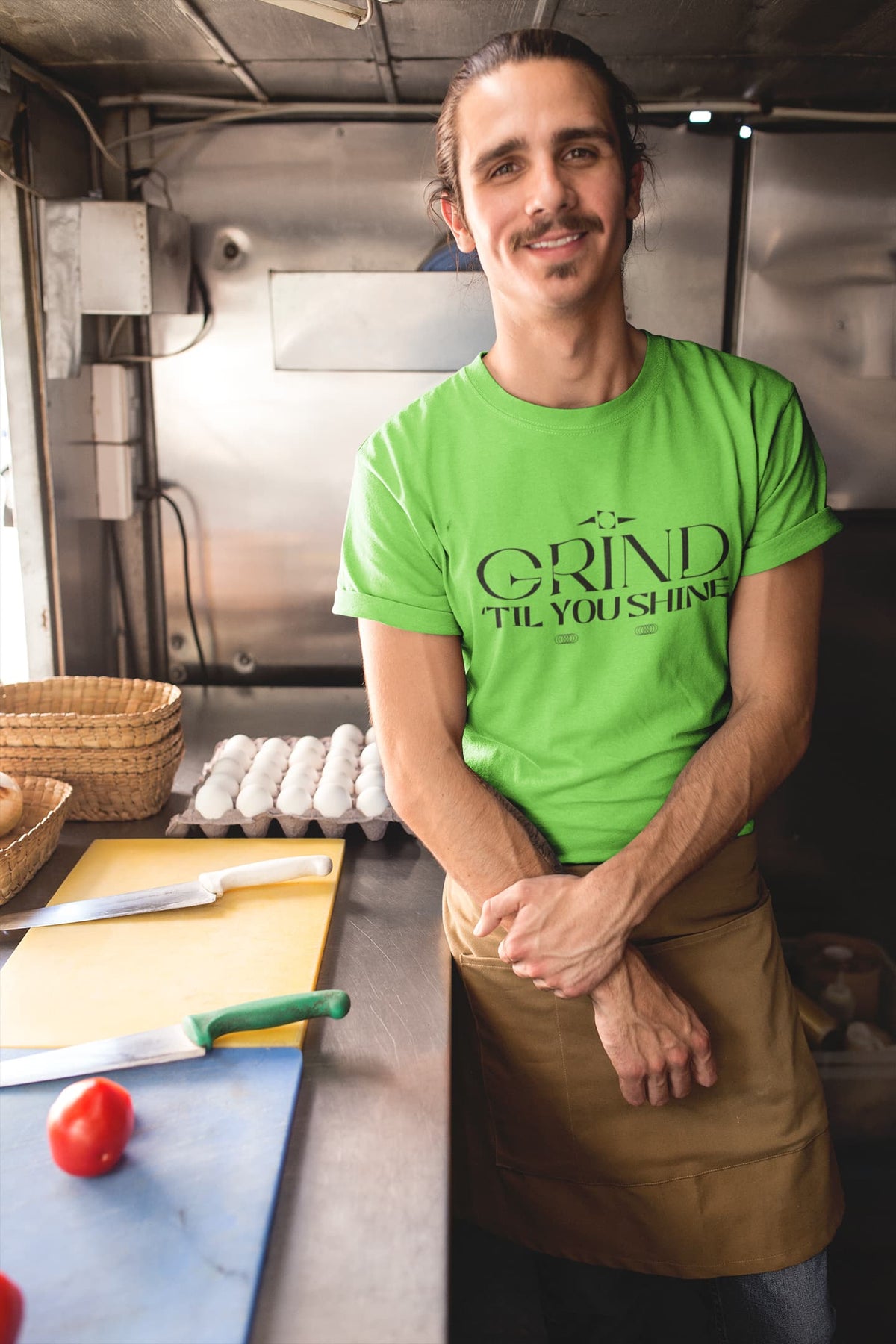 Person wearing a green t-shirt with 'Grind Til You Drop' in a kitchen setting
