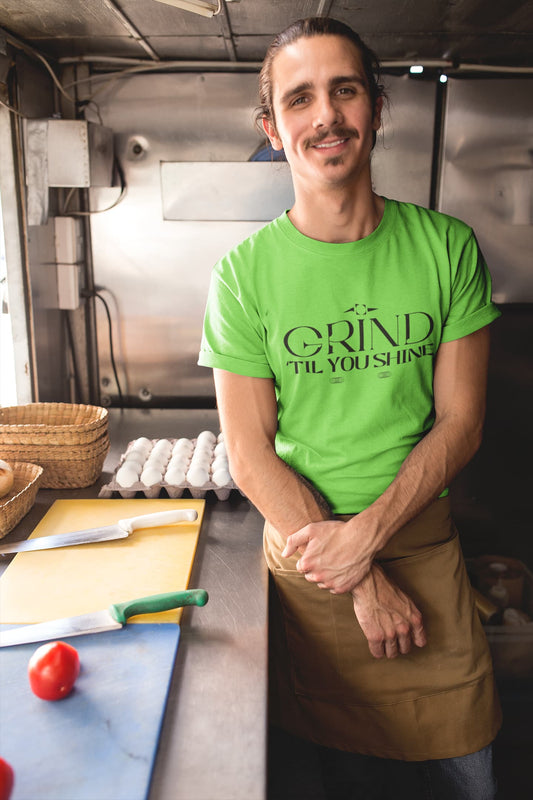 Person wearing a green t-shirt with 'Grind Til You Drop' in a kitchen setting
