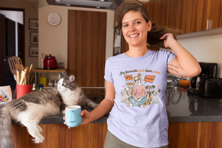 Woman in a kitchen wearing a t-shirt with a cat graphic and text, holding a mug.