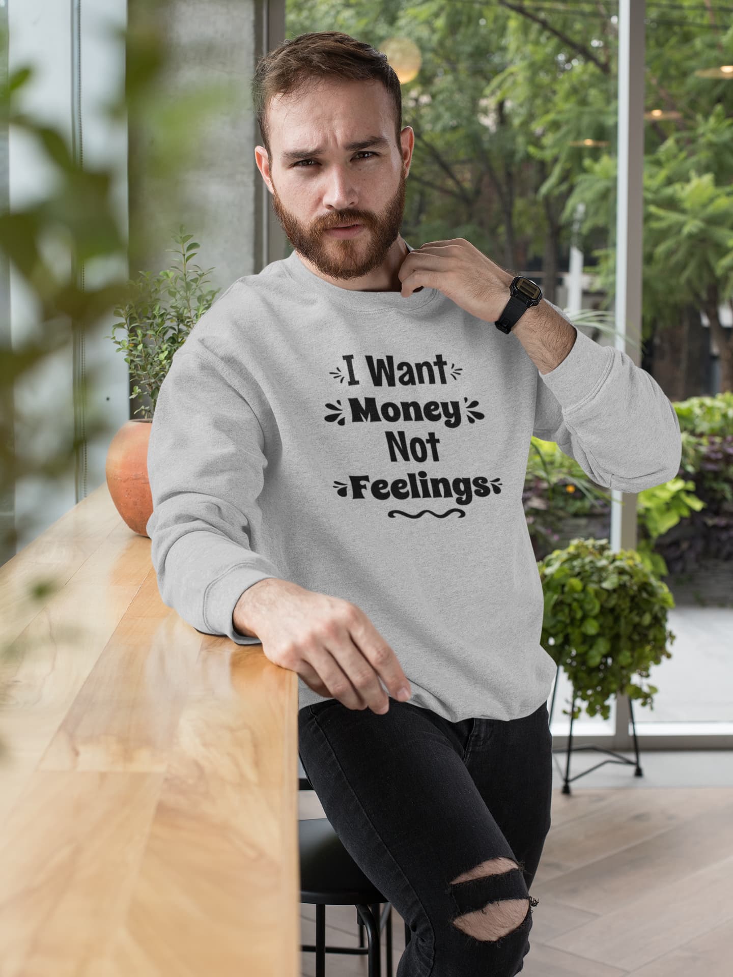 Man wearing a gray sweatshirt with text, sitting in an outdoor setting.