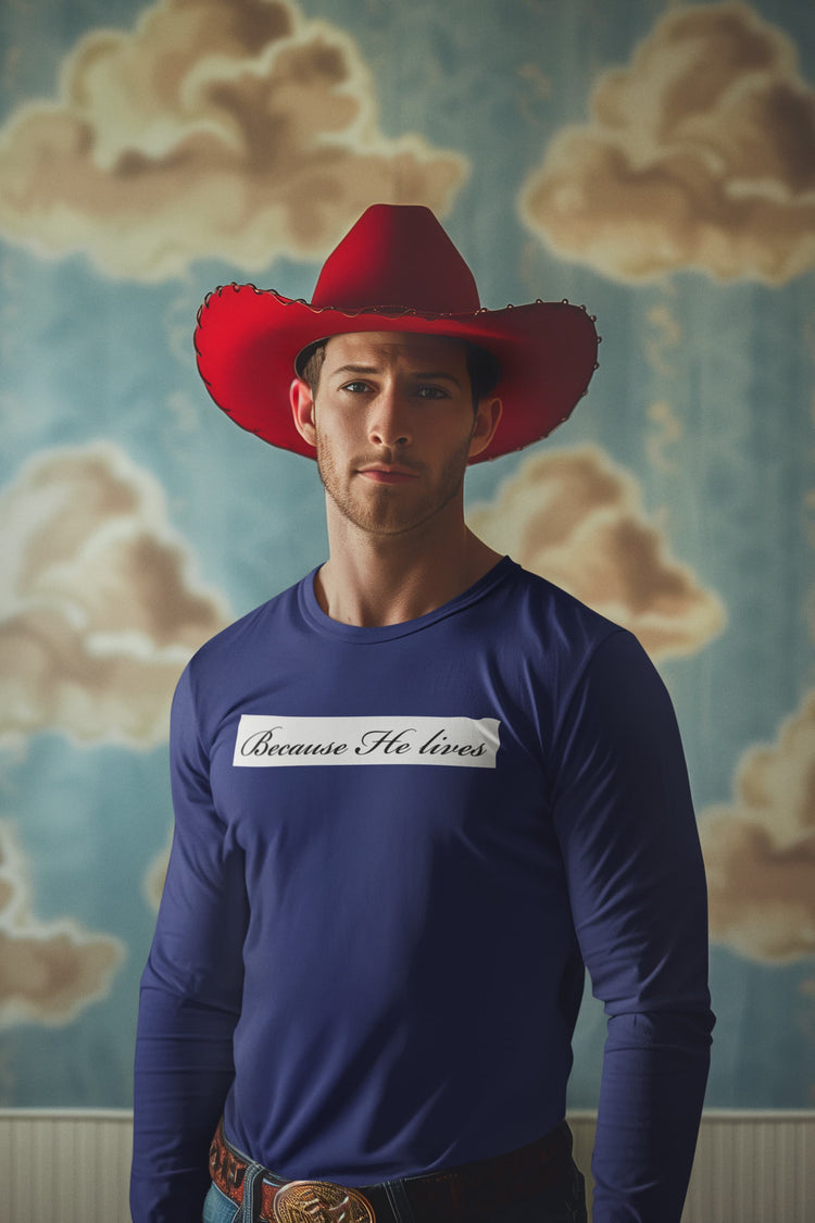 Man wearing a red cowboy hat and blue long-sleeve shirt with text, standing against a cloud-patterned wall.