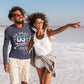 Two people walking on a salt flat with clear blue skies.