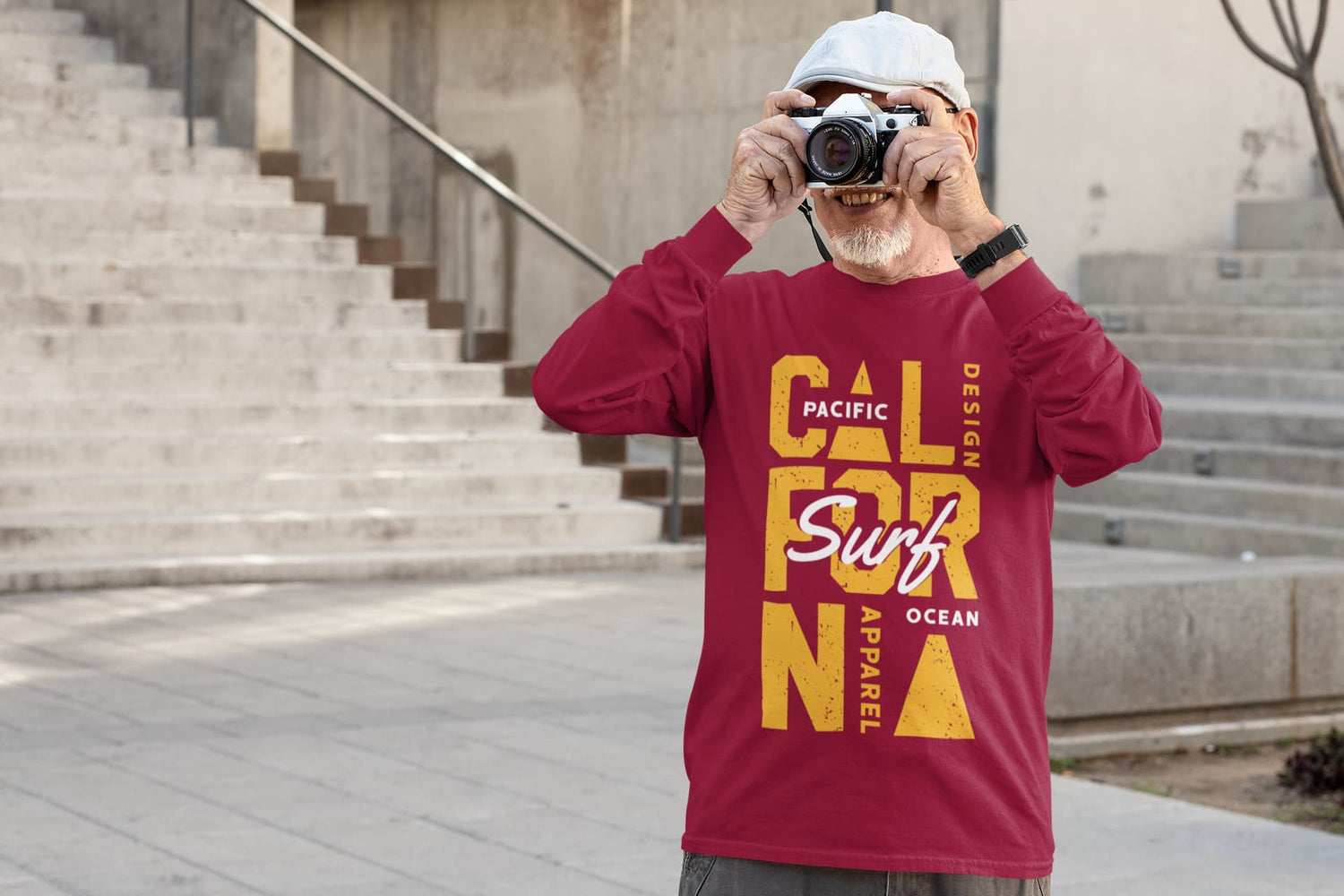 Man taking a photo with a camera, wearing a red t-shirt with yellow text, on a staircase.