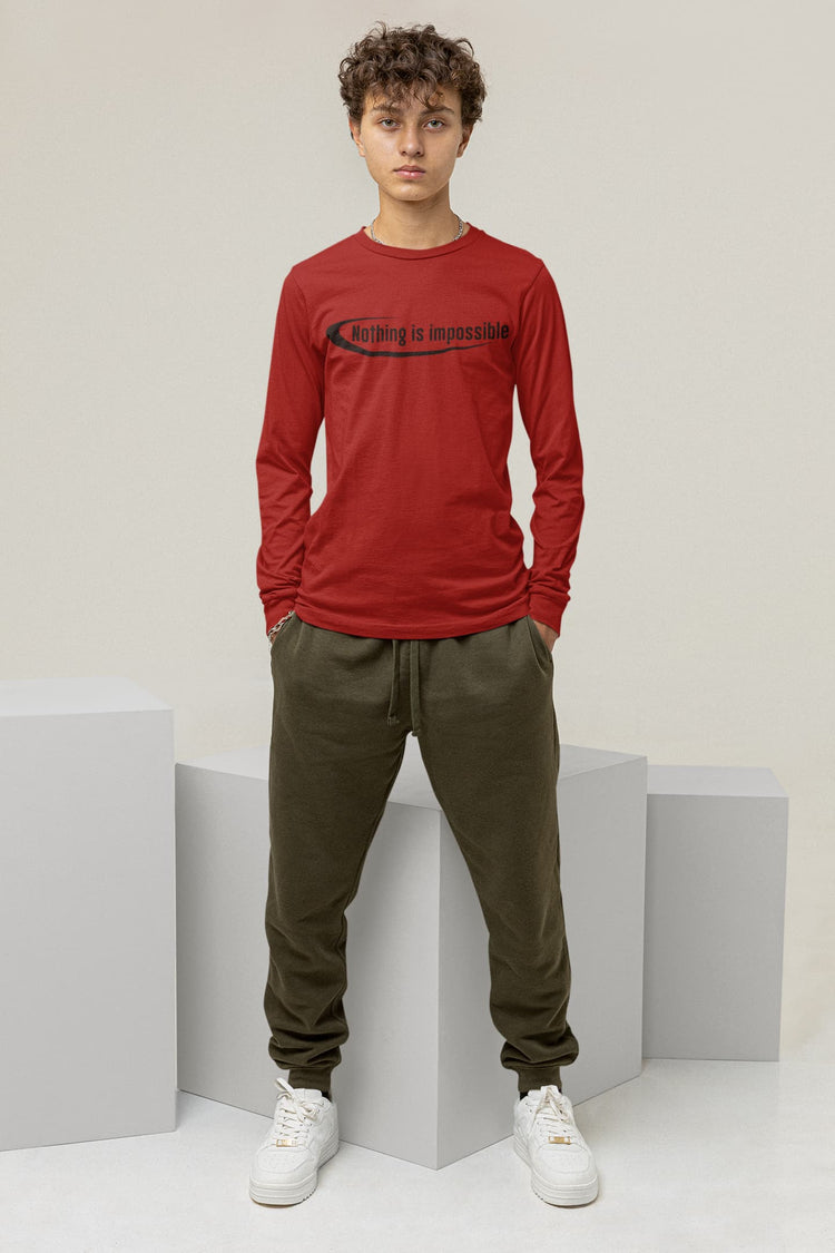 Person wearing a red long-sleeve shirt with text and green pants, standing on a white platform.