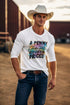 Man wearing a white t-shirt with colorful text and a cowboy hat in a desert setting.