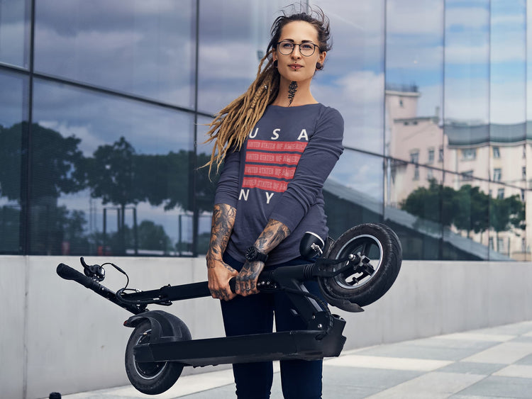 Woman holding a folded electric scooter with a modern building in the background