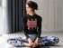 Woman sitting in a yoga pose wearing a black sweatshirt with &