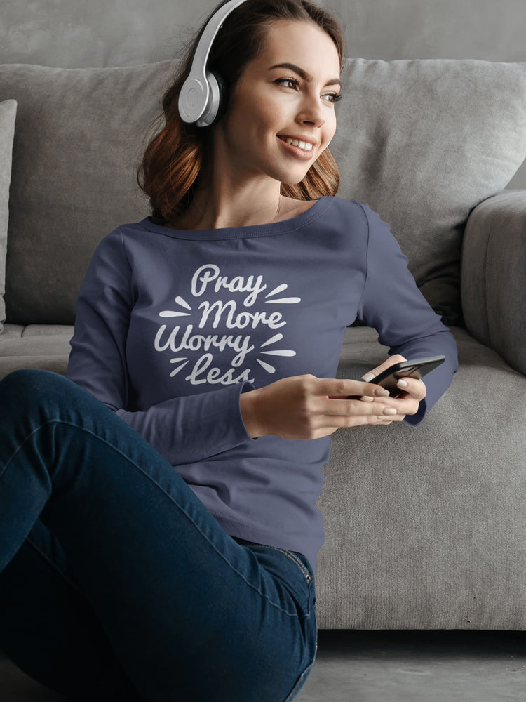 Woman sitting on a couch wearing headphones and a shirt with text, holding a phone.