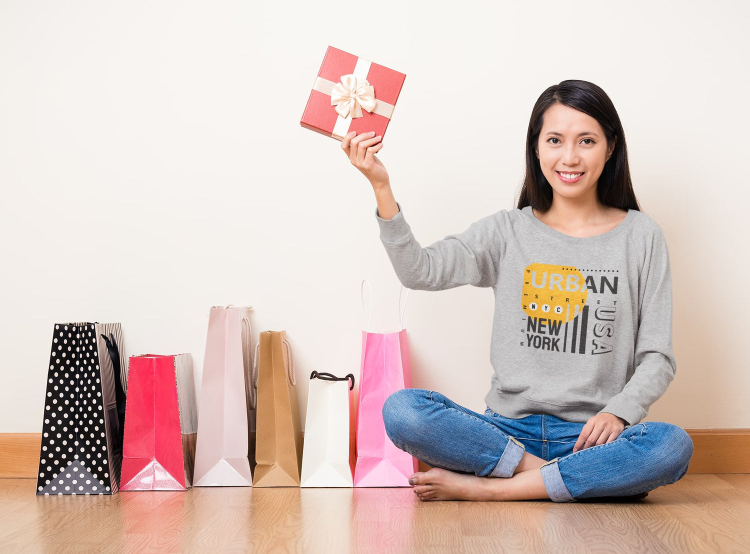 Woman holding a gift box with shopping bags on the floor