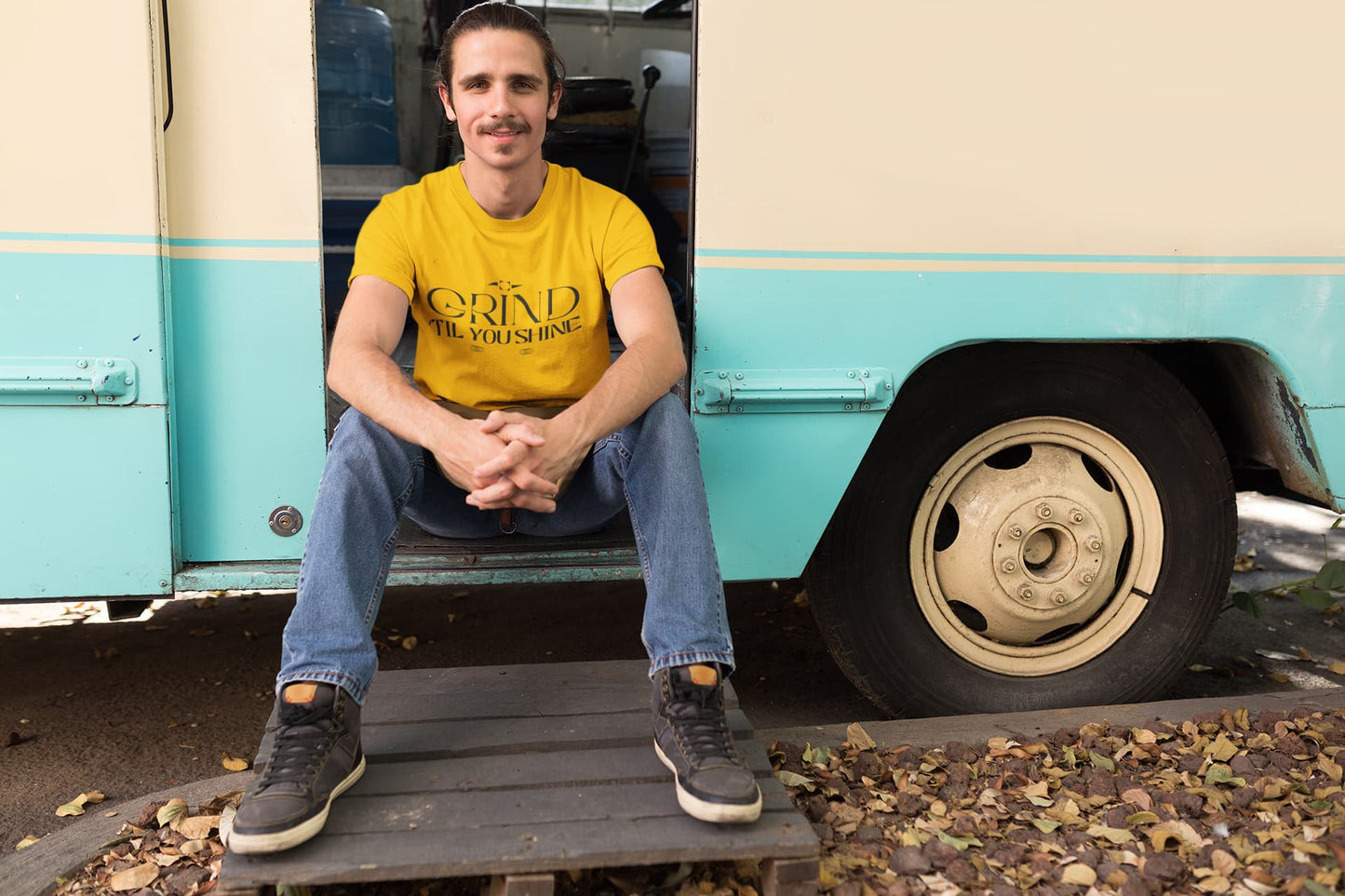 Man sitting on a vintage teal and beige RV with 'Wendy's' logo.