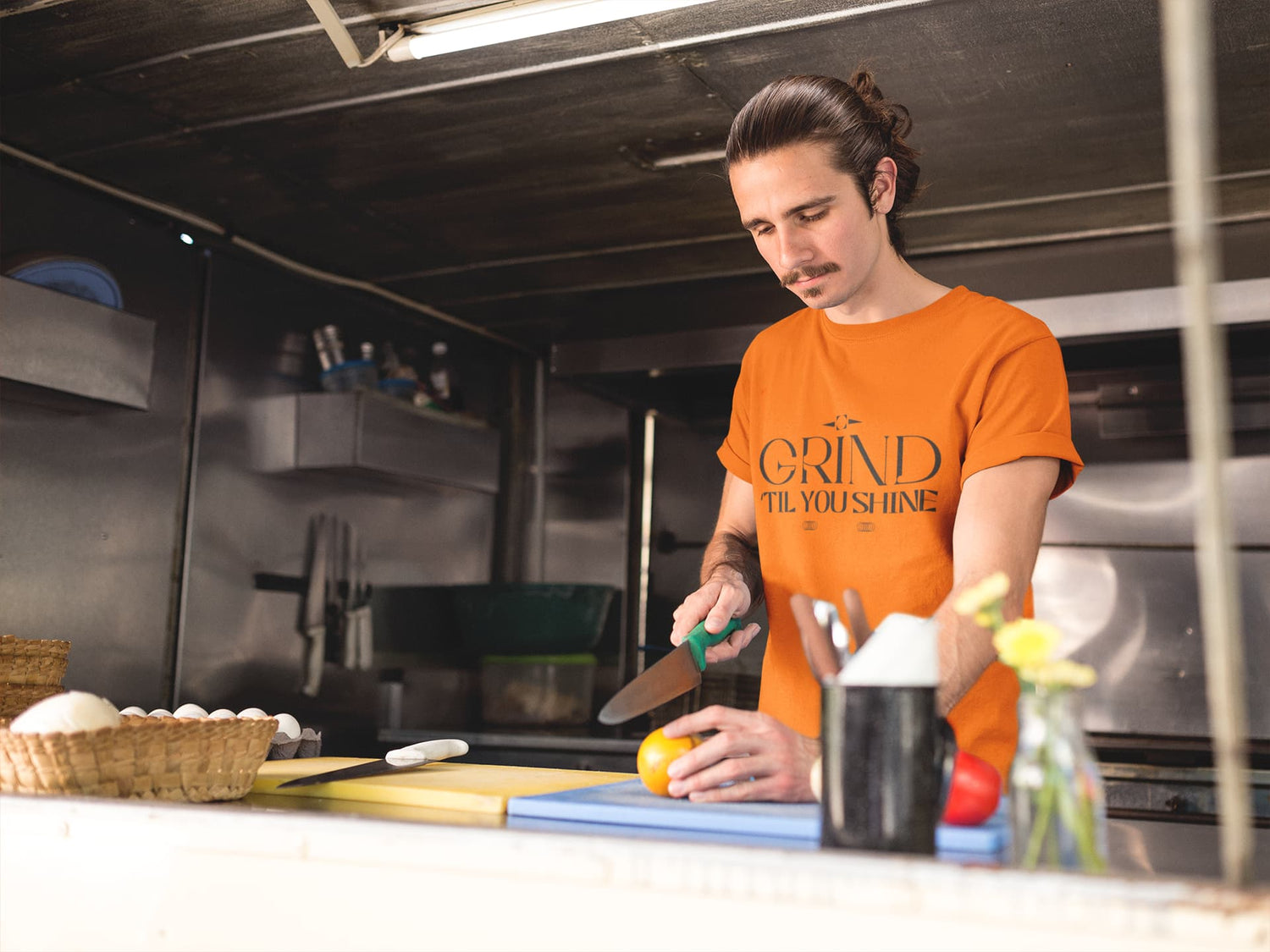 Person in an orange shirt preparing food in a kitchen
