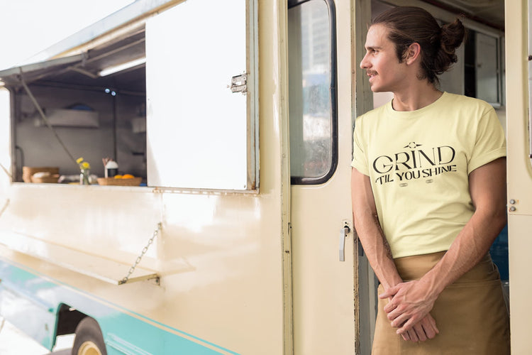 Person standing in front of a food truck wearing a yellow t-shirt with text.