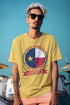 Man wearing a yellow t-shirt with a Texas-themed design against a blue sky.
