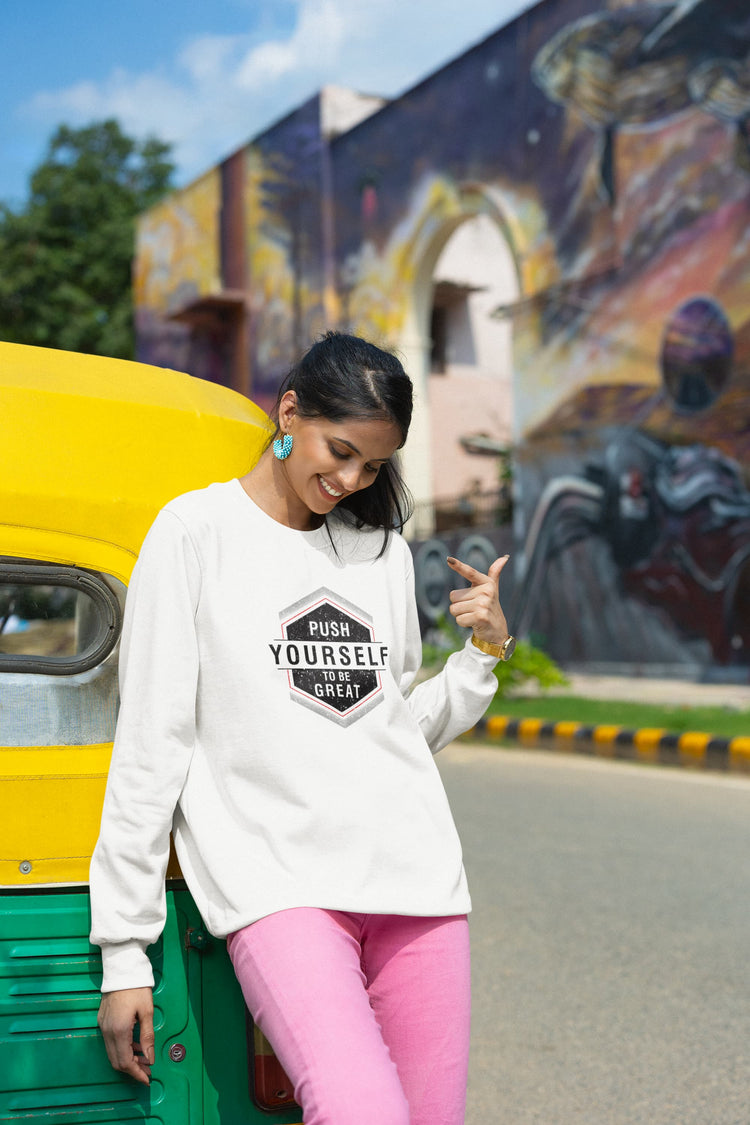 Woman in a white sweatshirt with text pointing towards a colorful mural on a street.
