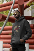 Man wearing a black hoodie with 'DREAMS DON'T EXPIRE' text, standing outdoors.