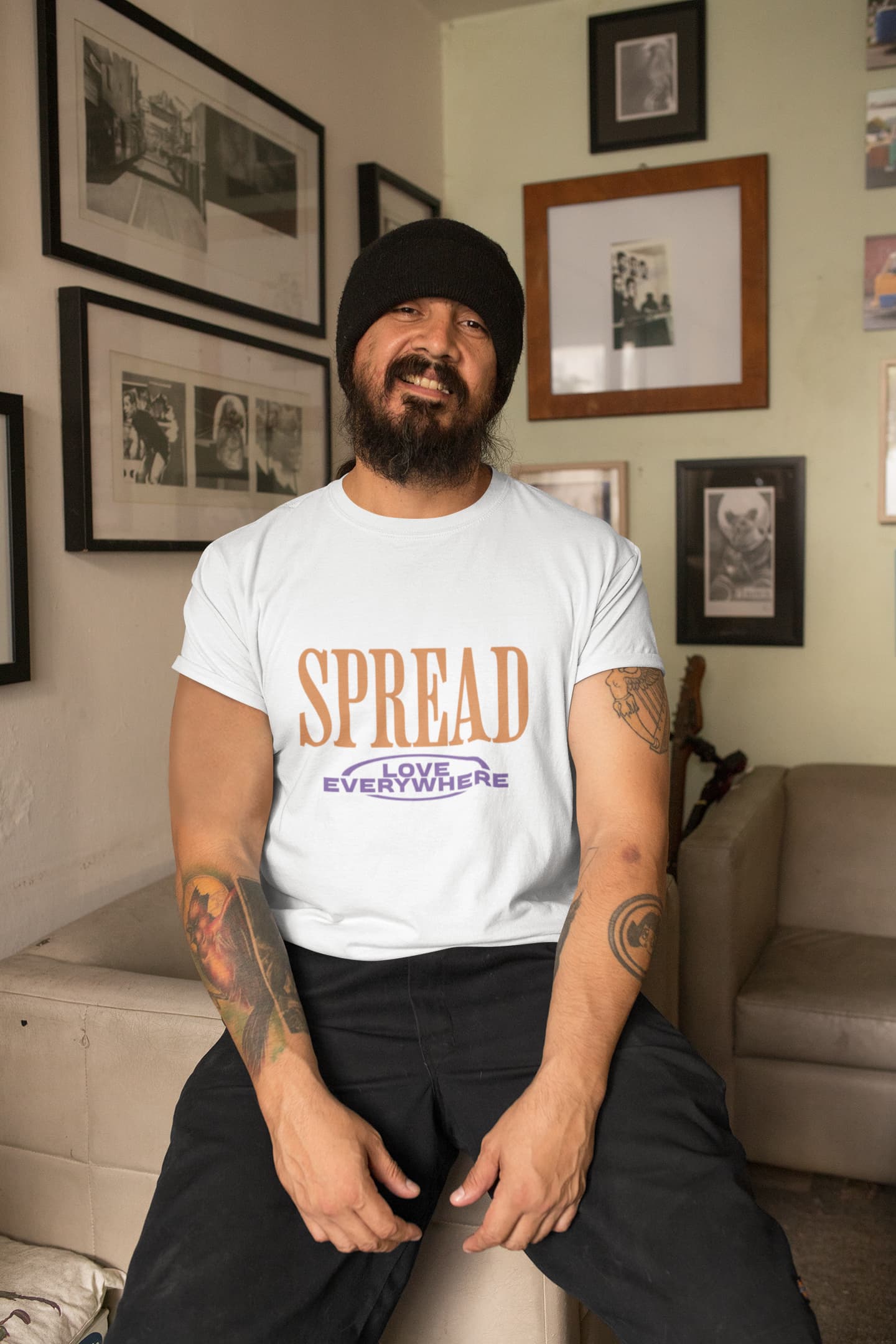 Man wearing a white t-shirt with 'SPREAD LOVE EVERYWHERE' text in a living room.