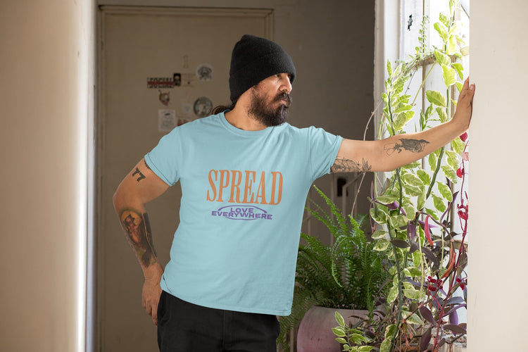 Man wearing a light blue t-shirt with text, standing indoors with plants around.