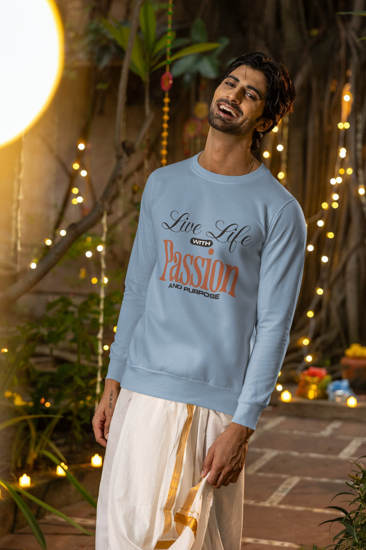 Man wearing a light blue sweatshirt with text, standing in a decorative outdoor setting with lights and plants.