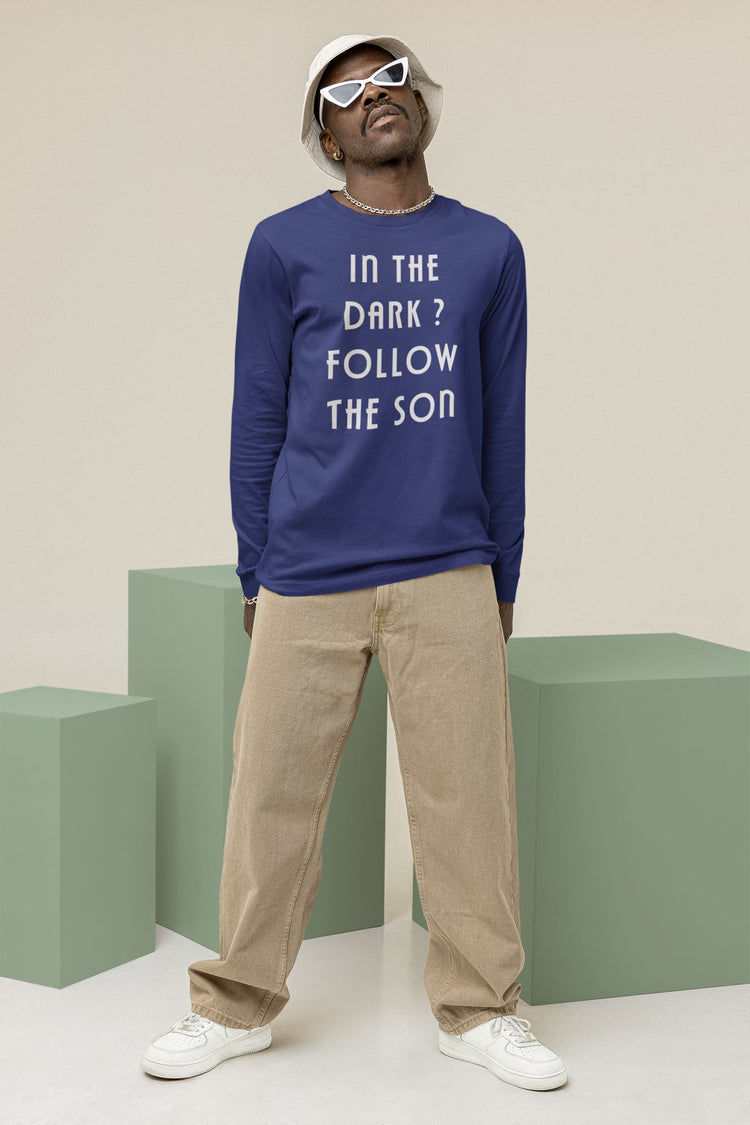 Man wearing a blue sweatshirt with text, beige pants, and white sneakers on a plain background