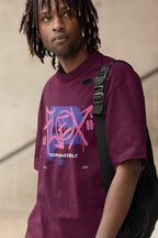Person wearing a purple t-shirt with a graphic design, standing against a neutral background
