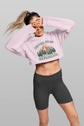 Person wearing a pink cropped hoodie with a nature-themed design and black shorts on a gray background
