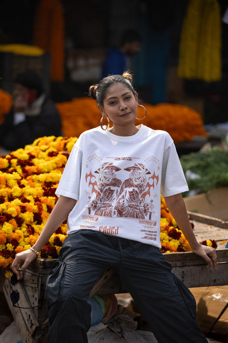 Woman sitting among flowers wearing a white t-shirt with graphic design