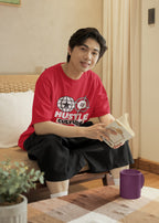Person wearing a red t-shirt with text, sitting on a couch holding a book.
