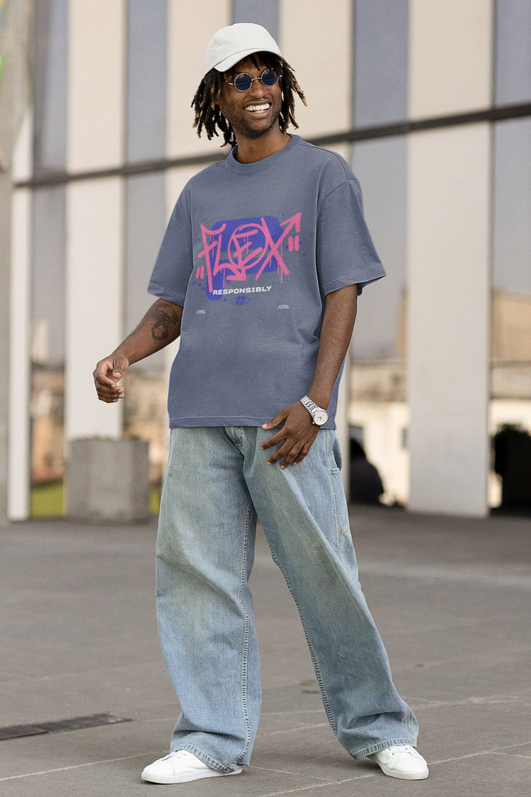 Person wearing a gray t-shirt with colorful design and blue jeans standing outdoors.