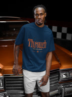 Man wearing a blue t-shirt with 'Through' text standing in front of a vintage car.