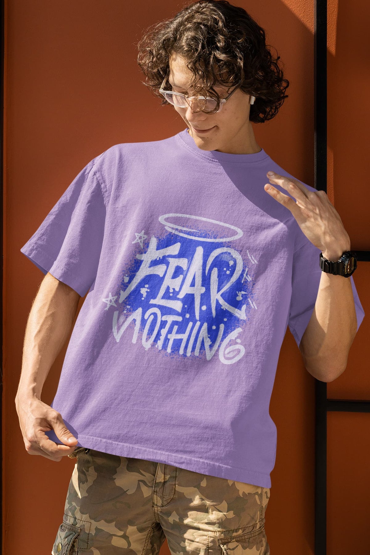 Person wearing a purple t-shirt with 'FEAR NOTHING' text, standing against an orange wall.