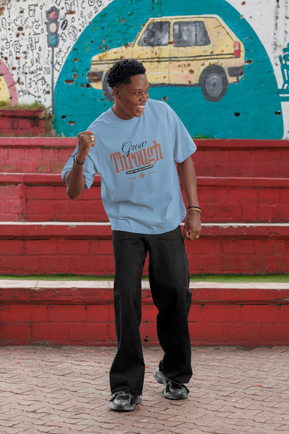 Person wearing a light blue t-shirt with text, standing in front of a colorful mural.