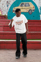 Person wearing a white t-shirt with text, standing in front of a colorful mural.