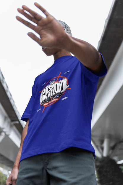 Person wearing a blue t-shirt with a graphic design, standing outdoors.