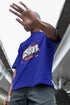 Person wearing a blue t-shirt with a graphic design, standing outdoors.