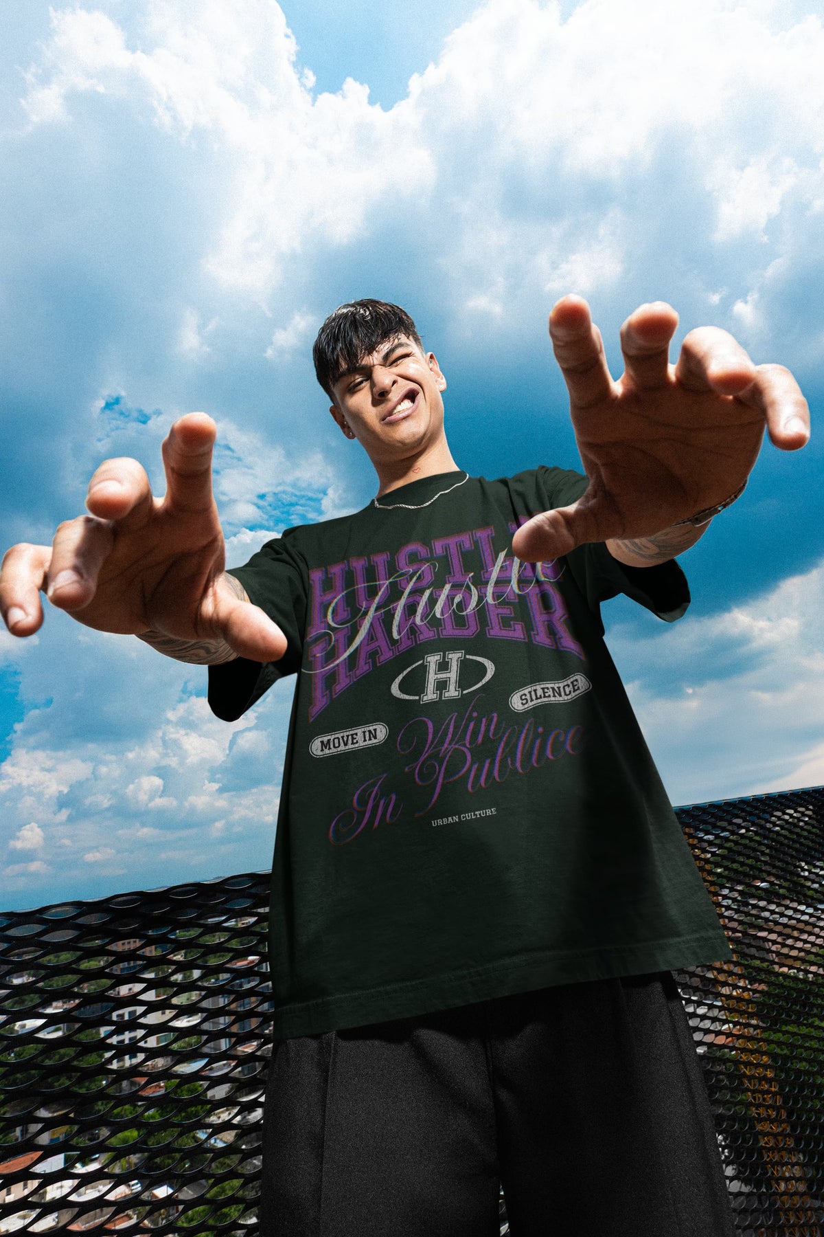 Person wearing a black t-shirt with visible branding against a blue sky.