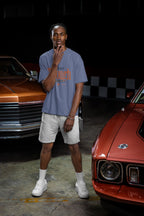 Man standing between two classic cars in a garage
