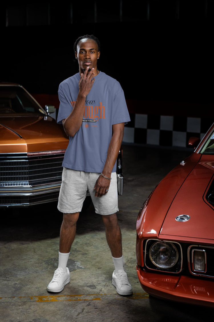 Man standing between two classic cars in a garage